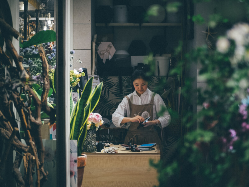Florist flower arranging surrounded by plants and flowers